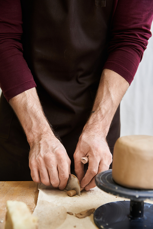 Dedicated male in apron making some pottery in studio.