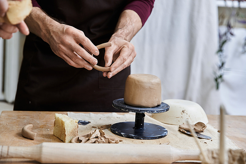 Sophisticated male in apron making some pottery in studio.