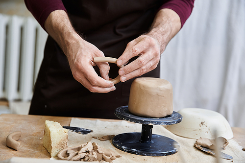 Talented young male in apron making some pottery in studio.