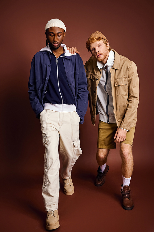 Two stylish multicultural men striding down runway together.