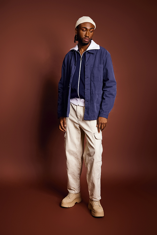 Handsome young man confidently struts in stylish blue jacket and white pants.