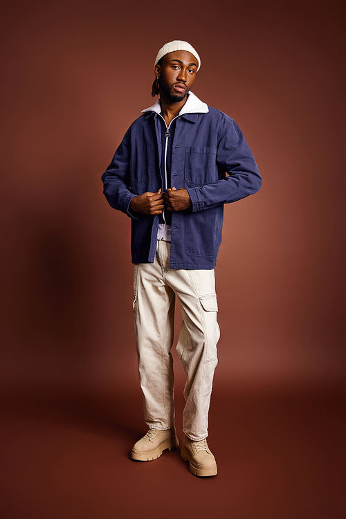 A handsome young African American man in a blue jacket and white pants.