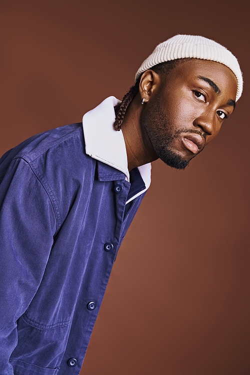 Handsome young African American man in a blue shirt and white hat.