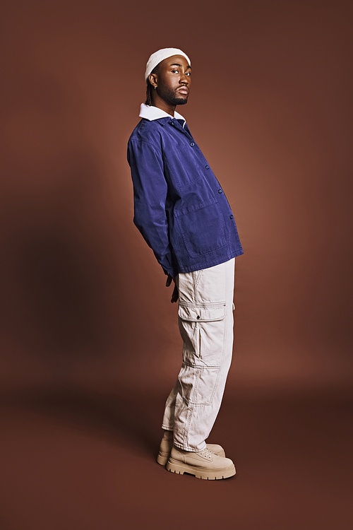 A handsome young African American man in a blue jacket and white pants.