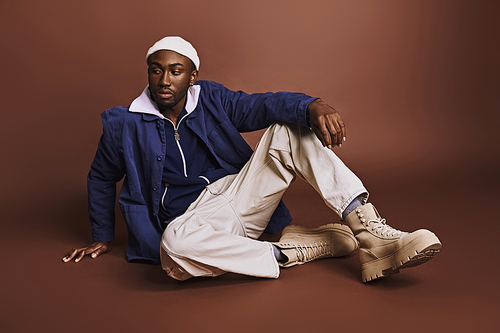 Young African American man sitting cross-legged on ground.