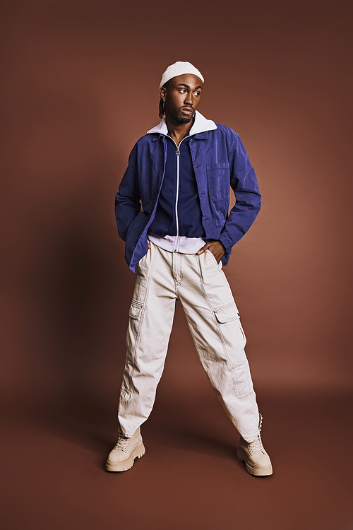 An African American man stands with hands on hips in a stylish outfit.