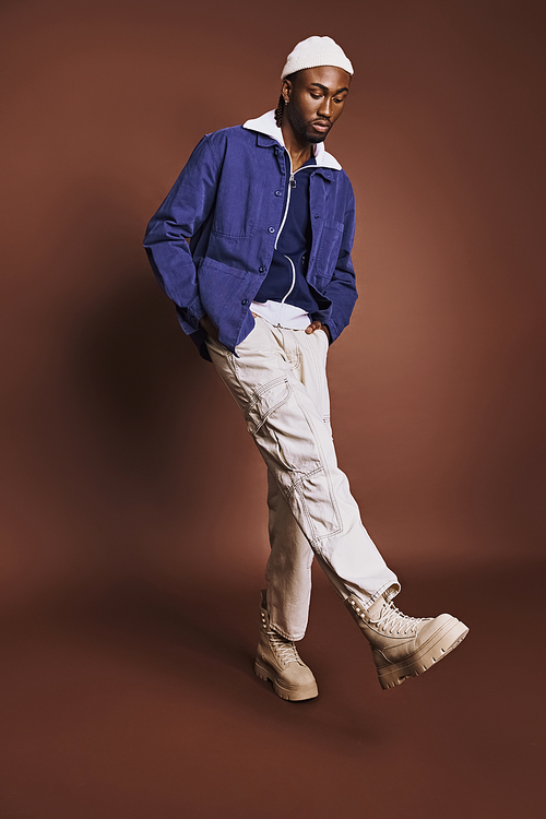 Handsome young African American man wearing stylish blue shirt and white pants.