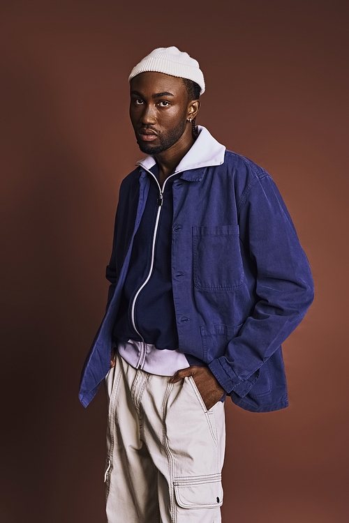 Handsome young African American man in a blue jacket and white hat.