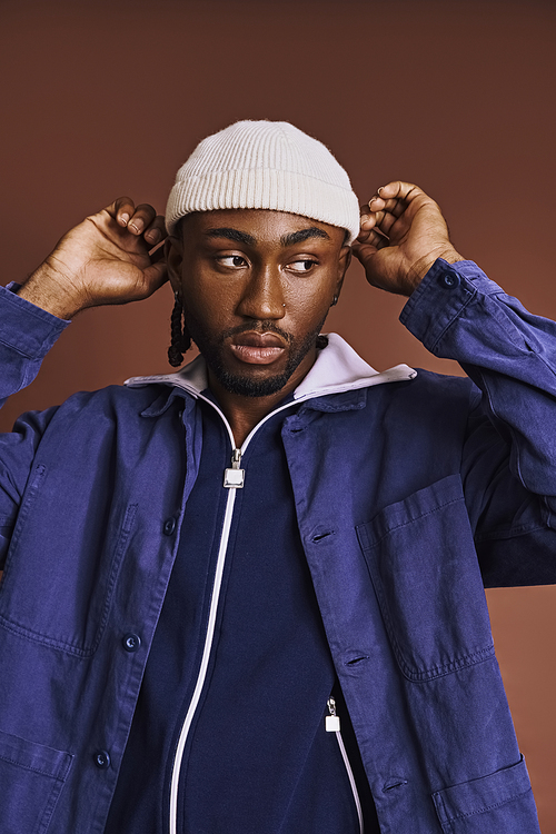 A handsome young Afro-American man wearing a blue jacket and a white hat.