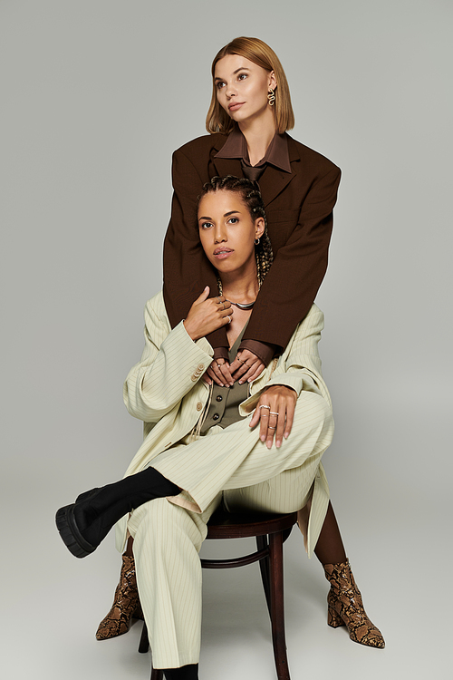 Two young women embrace in cozy attire, radiating joy and love amid the autumn glow.