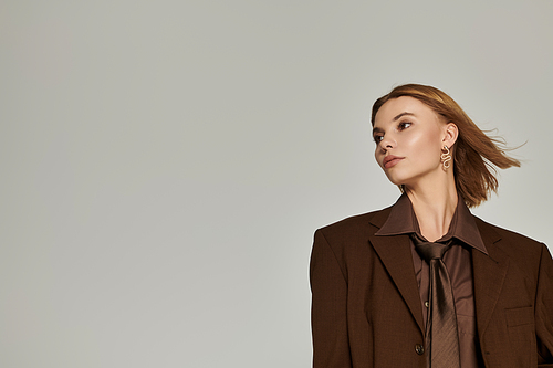 Sophisticated blonde woman in brown warm clothing posing actively.