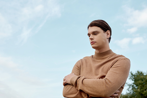 A well-dressed man stands contemplatively in an autumn field, embracing the calm beauty of nature.