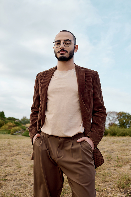 A fashionable man stands gracefully in a serene autumn landscape, radiating confidence and style.