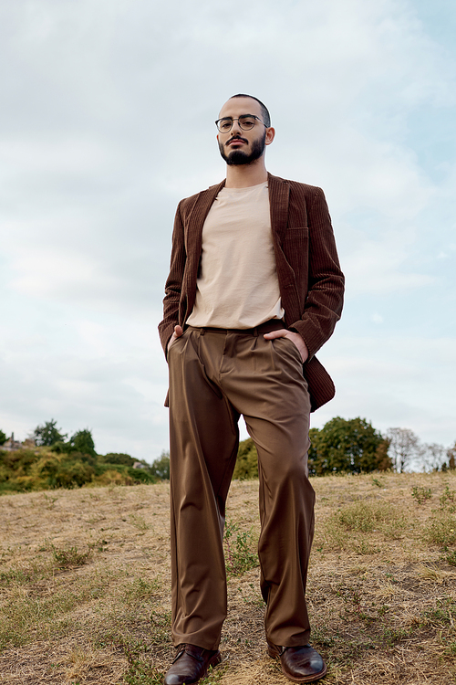 A well-dressed man stands poised in a serene autumnal field, surrounded by nature vibrant hues.