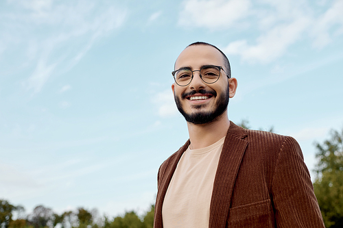 A well-dressed man smiles warmly while embracing the beauty of an autumn day in a scenic field.