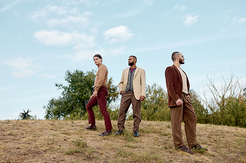 Three stylish male models pose in a tranquil autumn landscape, exuding charm and elegance in nature.