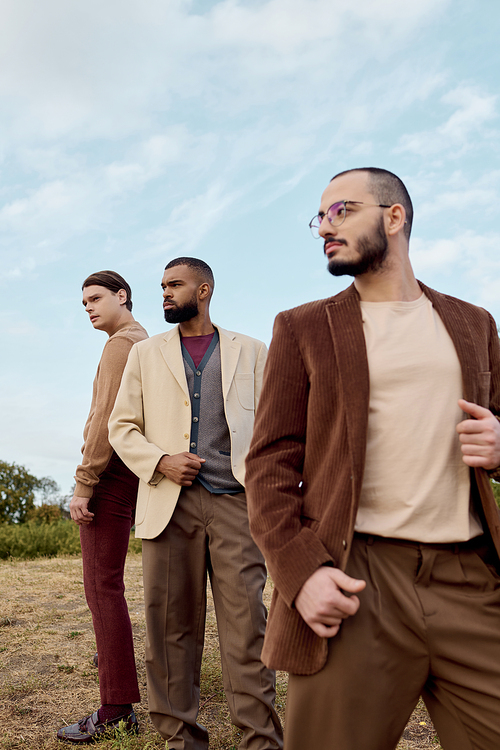 Handsome men dressed in chic autumn attire strike poses in a beautiful natural landscape during fall.