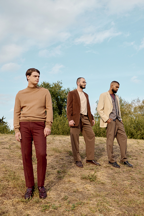 Fashionable men showcase autumn styles while enjoying a picturesque day in a natural field.