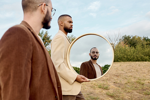 Two handsome men in fashionable fall attire stand in a natural setting, reflecting autumnal beauty.