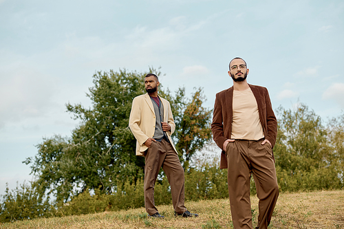 Handsome men showcase trendy autumn attire while posing amidst nature's vibrant hues.