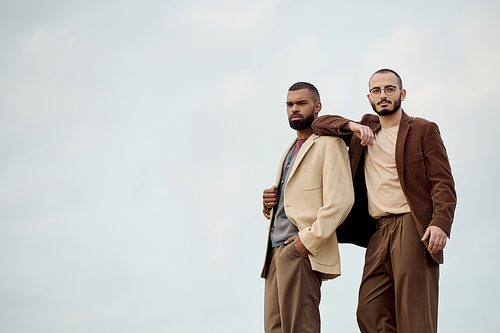 Handsome men in fashionable outfits pose confidently amidst an autumn landscape, capturing seasonal elegance.