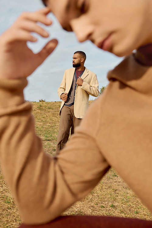 Handsome men display fashionable autumn outfits against a serene natural backdrop, embodying seasonal elegance.