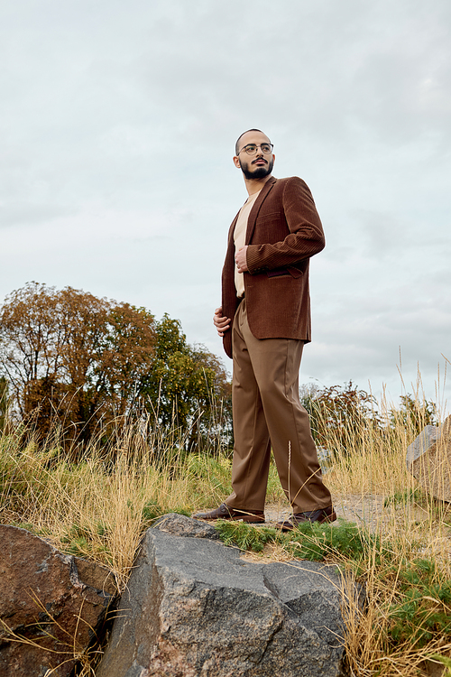 A dapper man stands proudly in a field, embracing the beauty of autumn with fashionable attire.