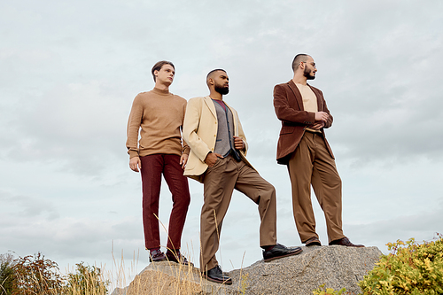 Handsome male models showcasing fashionable autumn attire stand confidently in a vibrant field.