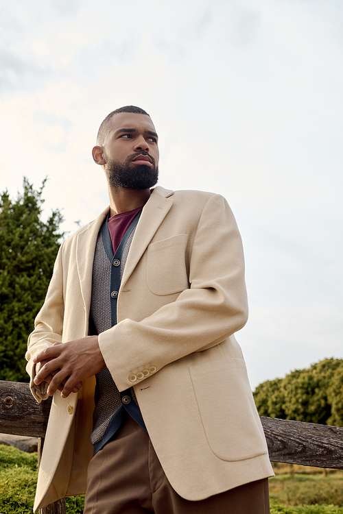 An elegantly dressed man enjoys an autumn day, blending fashion with the beauty of nature around him.