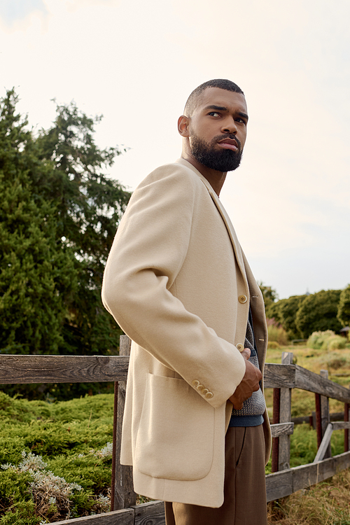 A handsome man showcases fall fashion while standing gracefully in a vibrant autumn landscape.