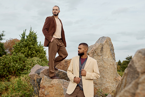 Handsome men pose confidently in stylish autumn outfits against a vibrant natural backdrop.