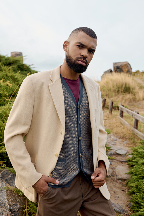 A fashionable man stands in a serene autumn landscape, highlighting natural beauty and style.