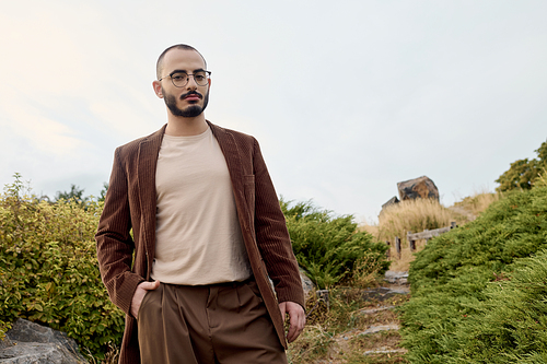 A handsome model strolls through a serene autumnal landscape, embodying seasonal style and grace.