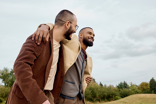 Two handsome men dressed in autumn attire share a joyful moment