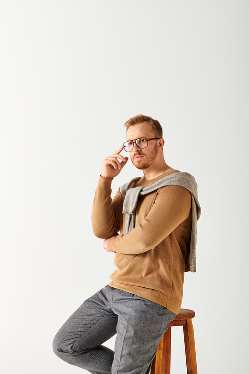 Handsome man in stylish attire posing actively on top of a wooden stool.