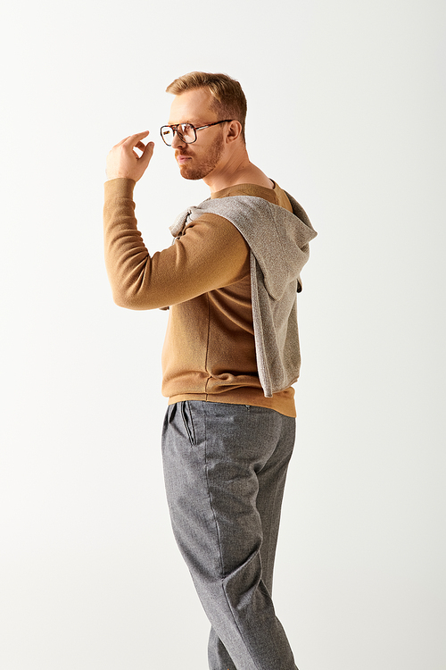 Handsome man in glasses and sweater standing confidently.