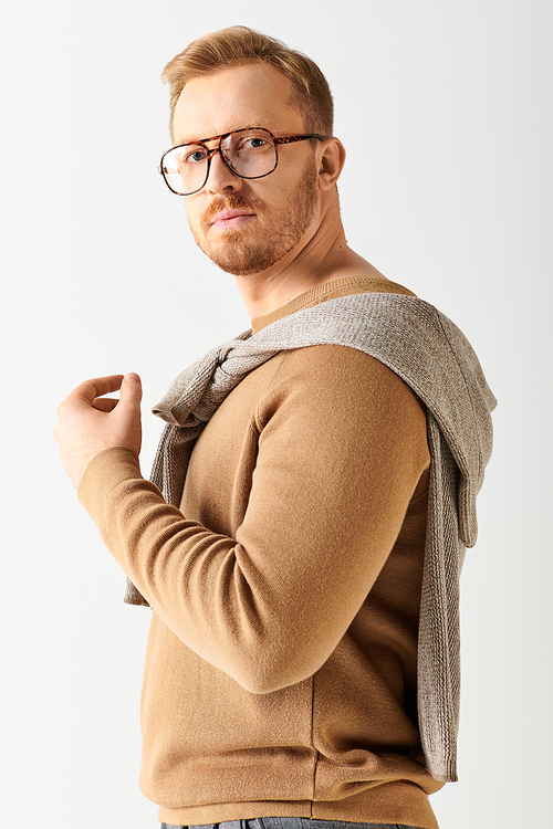 Handsome man in glasses and a sweater poses confidently.