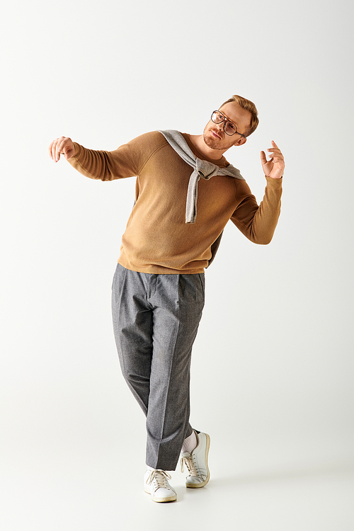 Handsome man actively posing in stylish brown shirt and grey pants.