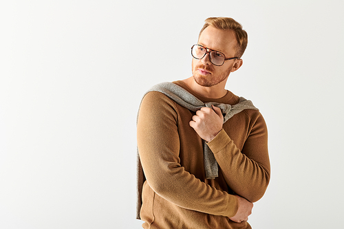 A man in glasses and a sweater strikes a stylish pose.