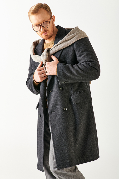 Handsome man in gray coat and glasses posing confidently.