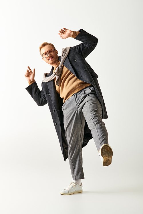 A stylish man in a trench coat gracefully dances with flair.