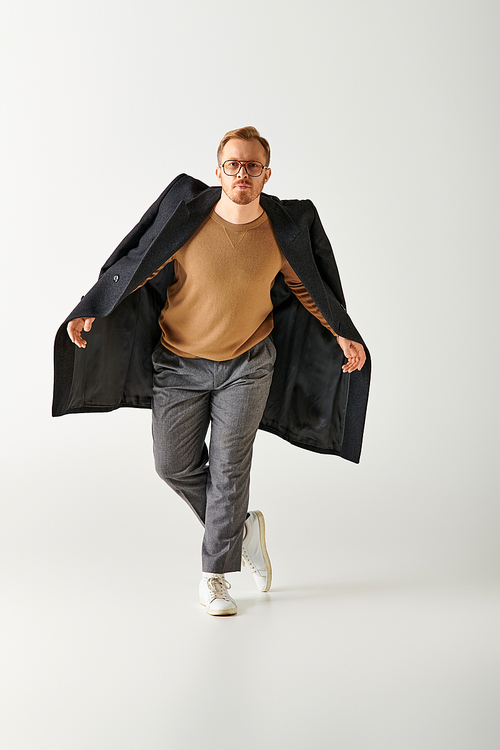 A handsome man actively posing in stylish brown shirt and black coat.