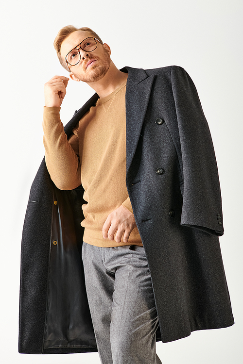 A man in glasses and a coat confidently poses for a portrait.