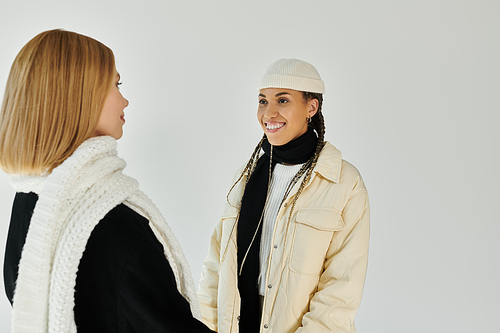 Two young women in stylish autumn attire share a joyful moment, radiating love and warmth.