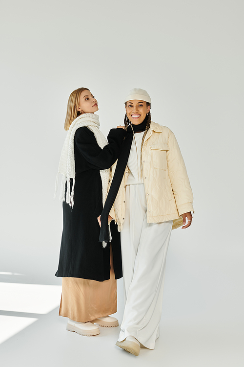 Two stylish young women share a joyful moment while dressed for a crisp autumn day.