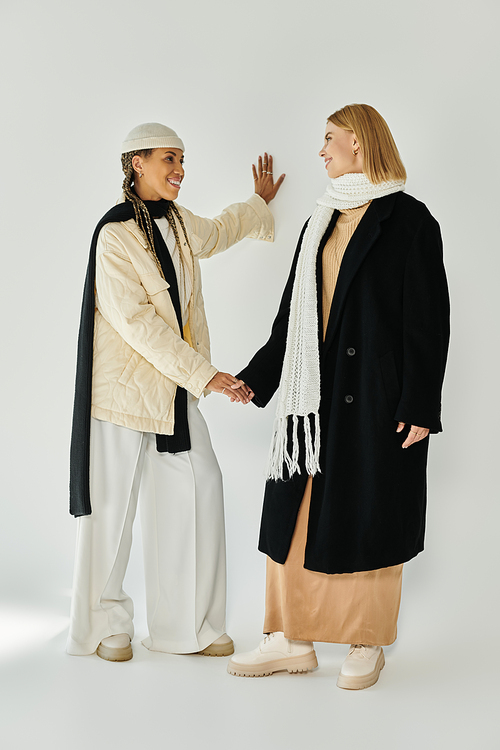 A beautiful lesbian couple dressed in autumn attire smiles and connects warmly indoors.