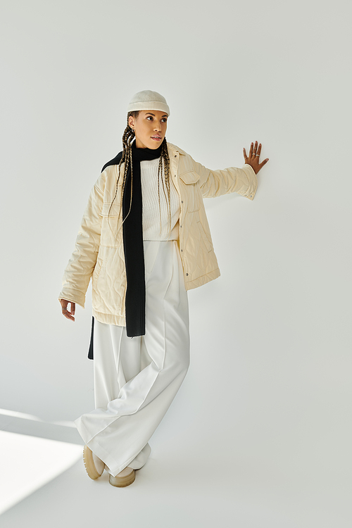 Appealing young woman in stylish warm attire posing on white backdrop.