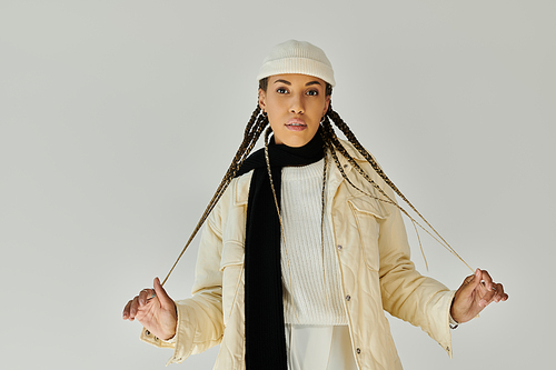 Stylish young woman in stylish warm attire posing on white backdrop.