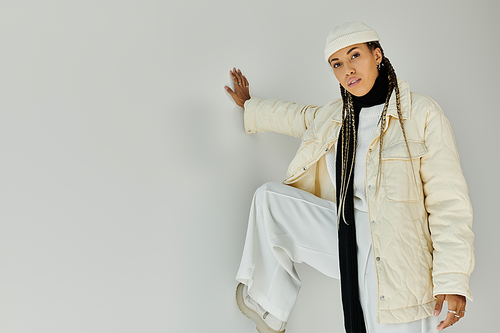 Chic young woman in stylish warm attire posing on white backdrop.