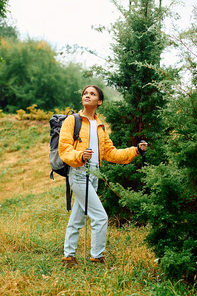 A young woman treks through the colorful autumn forest, embracing nature beauty with wonder.